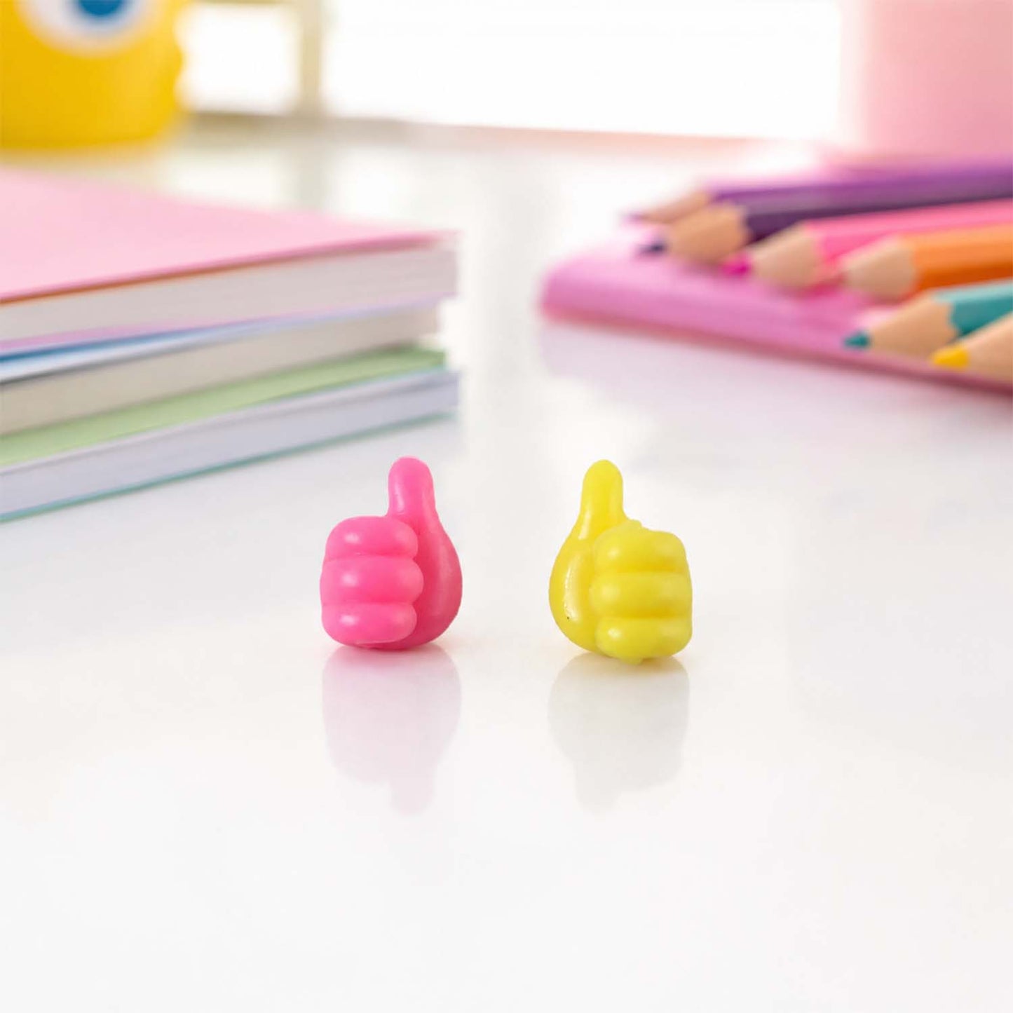 Pink and yellow thumb wire holder both colors on desk
