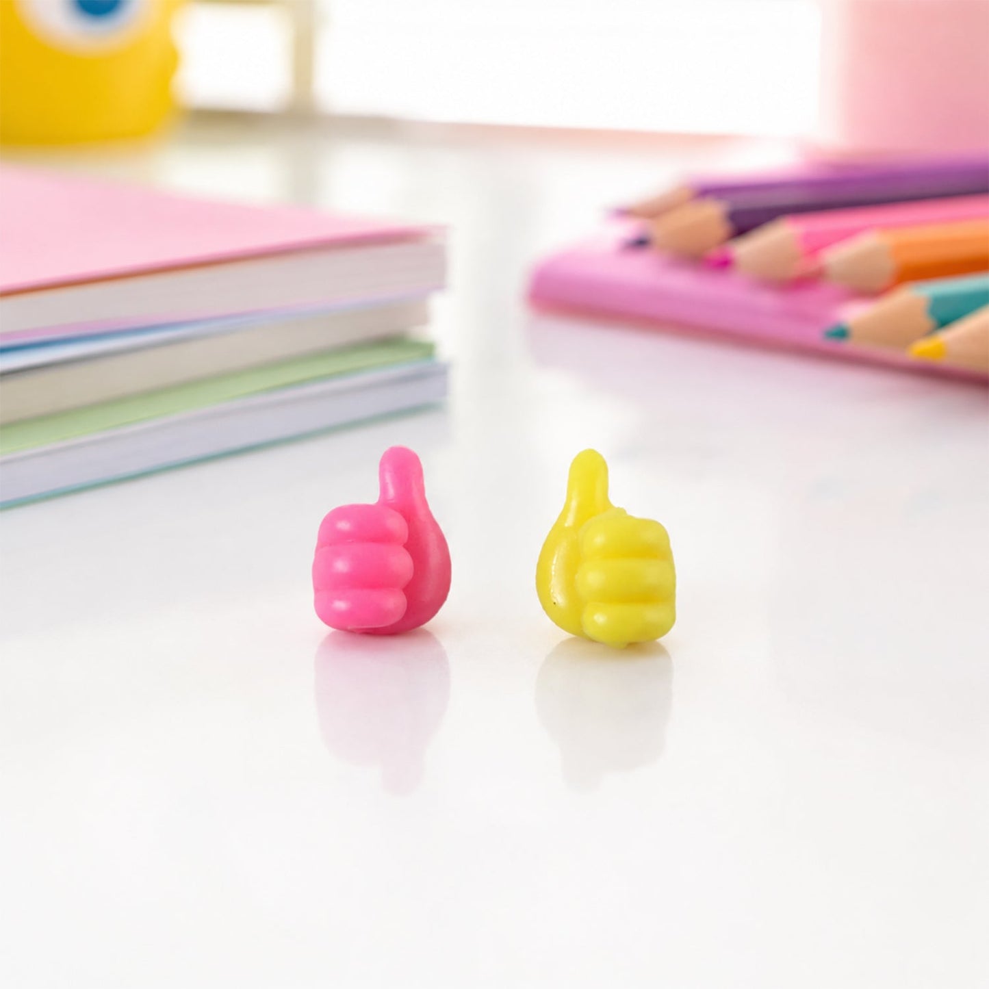 Pink yellow thumb wire holders on study table with books