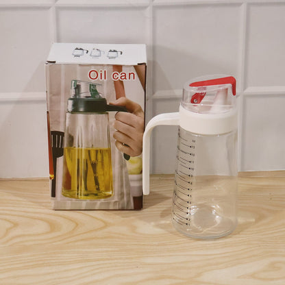 Glass Oil Dispenser Bottle 500ml with White Handle and Red Flip Cap Placed Beside its Retail Box Packaging on Wooden Surface